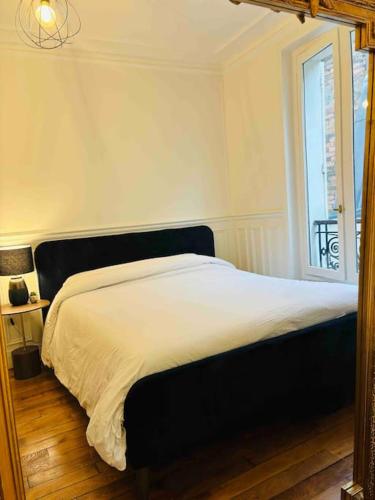 una camera da letto con un grande letto e una finestra di élégance à Neuilly : 5 min des Champs Elysées a Neuilly-sur-Seine