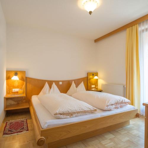 a bedroom with a large bed with white pillows at Ferienhof Neusacher Moser in Weissensee