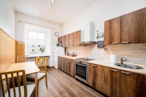 維爾紐斯的住宿－Heart of Senamiestis w King Bed, Full Kitchen，厨房配有木制橱柜、桌子和水槽。