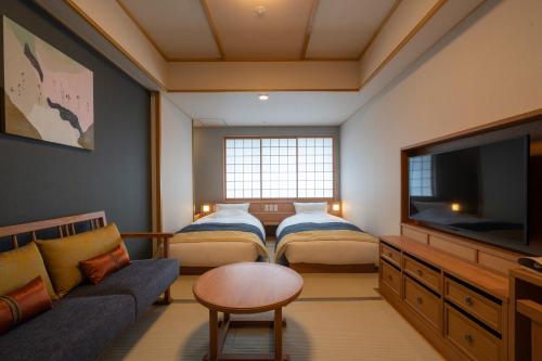 a room with two beds and a flat screen tv at Kyoto Umekoji Kadensho in Kyoto
