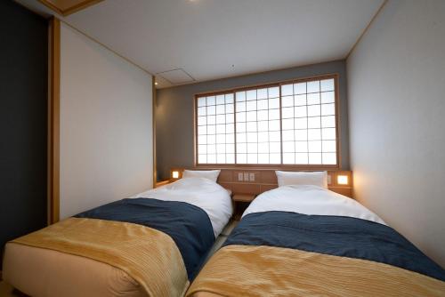 two beds in a room with a window at Kyoto Umekoji Kadensho in Kyoto