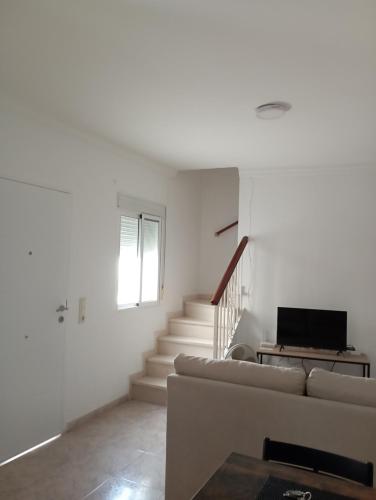 Sala de estar blanca con sofá y escaleras en El 20 en Barbate