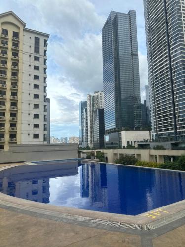 a large swimming pool in a city with tall buildings at Affordable Staycation Airbnb BGC in Manila