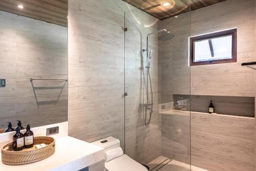 a bathroom with a glass shower and a toilet at La Fuga Siargao in Catangnan