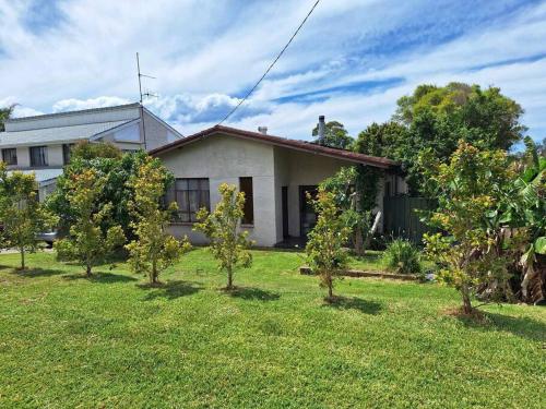 a small white house with trees in the yard at Clear Sand in Forster