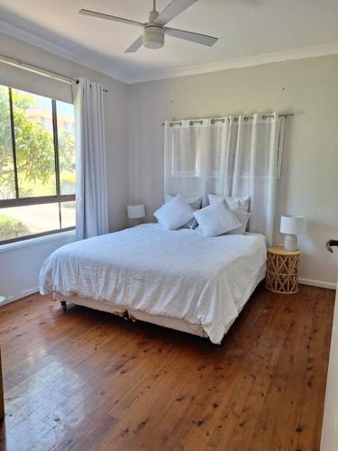 a bedroom with a white bed and a large window at Clear Sand in Forster