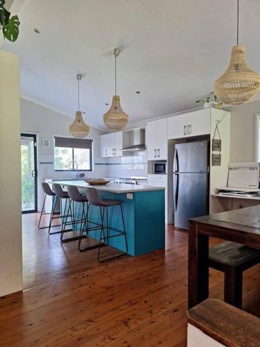 a kitchen with a blue island with bar stools at Clear Sand in Forster