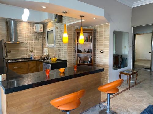 a kitchen with a bar with orange stools at GIZA NILE VIEW APT in Cairo