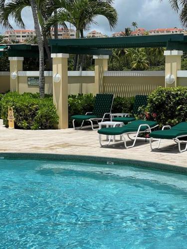 a swimming pool with two lawn chairs and a table at Carey Beach Villa in Humacao