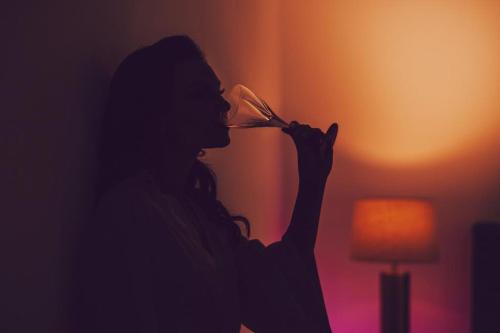 a woman drinking from a wine glass in a dark room at Penthouse View Aeroport Iasi in Iaşi