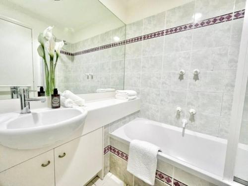 Baño blanco con lavabo y bañera en A Cozy 2B2B Apt Next To Carlton Garden W/ Parking, en Melbourne