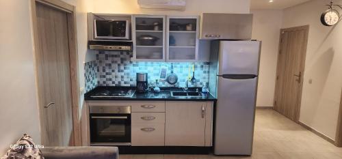 Una pequeña cocina con nevera y fregadero. en Super appartement vue sur mer et à 2 minutes de la plage de Martil., en Martil