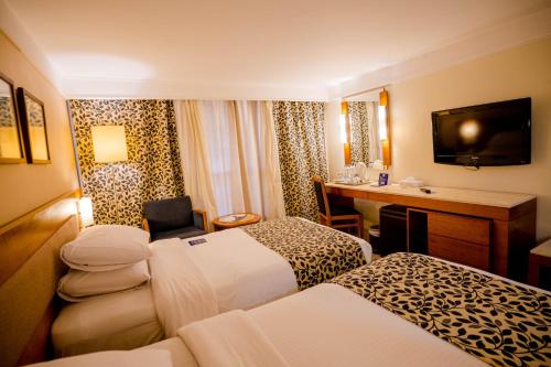 a hotel room with two beds and a desk at Marina Sharm Hotel in Sharm El Sheikh