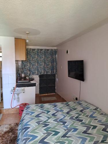 a small bedroom with a bed and a kitchen at Cottage 1 in Nairobi