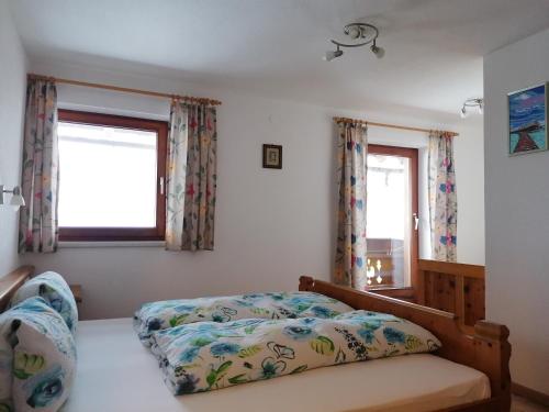 a bedroom with a bed and two windows at Embacher Marianne - Rotharlhof in Hopfgarten im Brixental