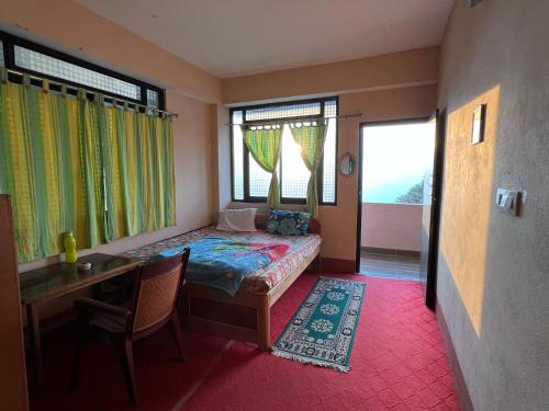 a bedroom with a bed and a desk and windows at Hangkhim Homestay in Ravangla