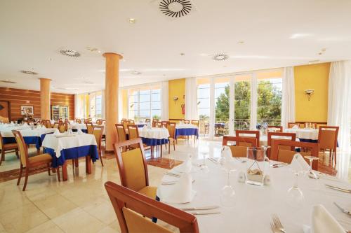 a dining room with white tables and chairs and windows at Bordoy Don Antonio in Paguera