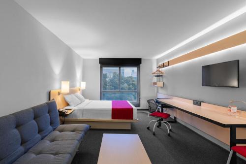 Habitación de hotel con cama y escritorio en City Express Plus by Marriott Guadalajara Expo, en Guadalajara