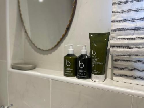 a bathroom shelf with two bottles of soap and a mirror at Beautifully appointed one-bedroom cottage in Shepreth