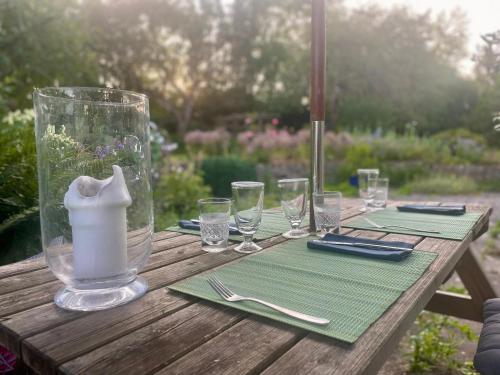 a wooden table with glasses and a vase on it at Beautifully appointed one-bedroom cottage in Shepreth
