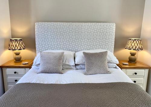 Beautifully appointed one-bedroom cottage في Shepreth: غرفة نوم مع سرير مع مصباحين في المواقف الليلية
