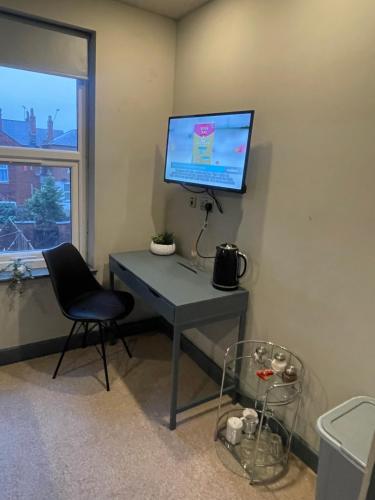 uma secretária com um monitor e uma cadeira num quarto em CV1 City Stays - Short & Long Term Accommodation No.6 em Coventry