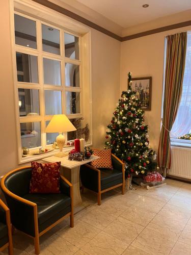 a christmas tree in a living room with a couch and a chair at Hotel GEO in Prague