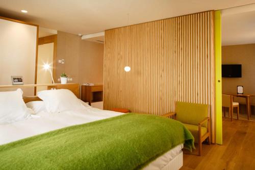 a bedroom with a large bed with a green blanket at Hotel Echaurren Relais & Châteaux in Ezcaray