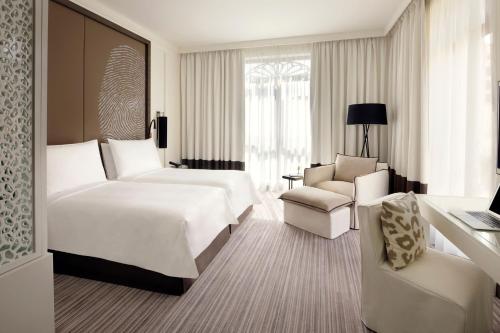 a hotel room with two beds and a chair at Hotel Boulevard, Autograph Collection in Dubai