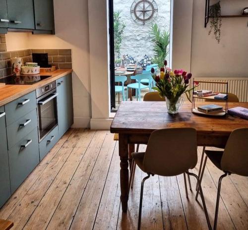a kitchen with a wooden table with chairs and a table with flowers at Mermaid Cottage Teignmouth by the beach SLEEPS 7 in Teignmouth