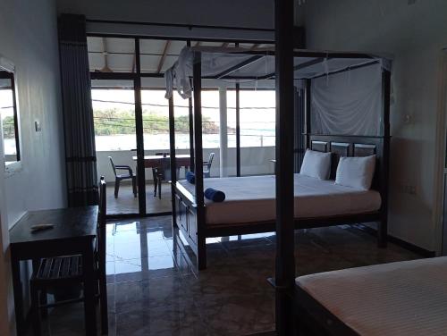 a bedroom with a four poster bed and a table at Sea Port Hiriketiya in Hiriketiya