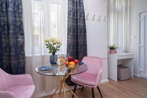 a dining room with a glass table and pink chairs at Amethyst Apartments - Acacia Studio in Budapest