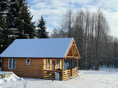a log cabin with snow on the roof in the snow at Domki Snopki in Pisz