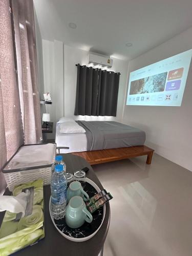 ein kleines Zimmer mit einem Bett und einem Tisch mit einem Tablett mit einer Teekanne in der Unterkunft Janis Home in Ban Noi Pho Kham