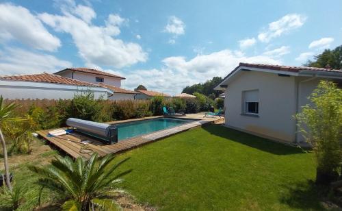 une cour arrière avec une piscine et une maison dans l'établissement Mimizan Jolie maison moderne avec piscine chauffée 4 Ch et jardin, à Mimizan