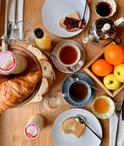 a wooden table topped with plates of food and fruit at Le Presbytère • Maison Flore in Chédigny
