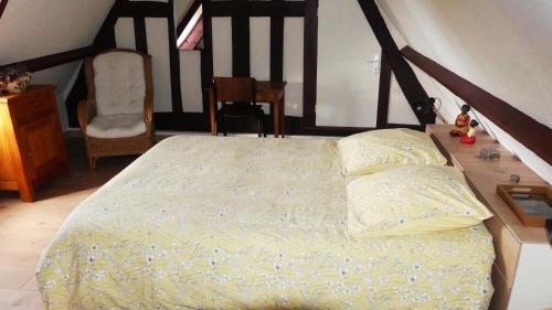 ein Schlafzimmer mit einem Bett und einem Stuhl in der Unterkunft Le Pressoir in Beaumesnil