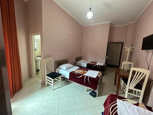 een slaapkamer met 2 bedden en een tafel en stoelen bij Hotel Zogu in Bulqizë