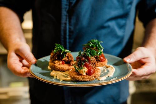 a person holding a plate with food on it at Trilith Guesthouse, Fayetteville, GA, a Tribute Portfolio Hotel in Fayetteville