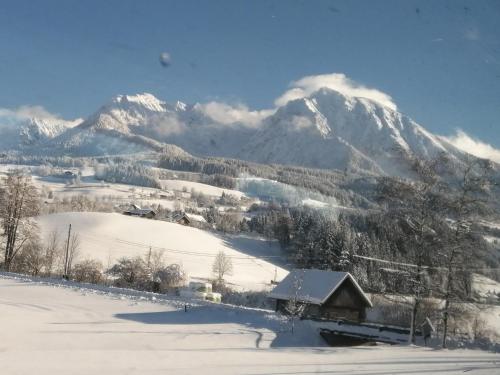 a snow covered mountain with a house in the foreground at Ferienhäuschen Nationalpark Gesäuse in Admont