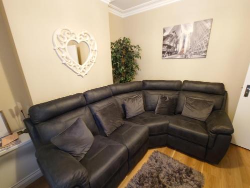 un sofá de cuero en la sala de estar con espejo de corazón en Helens House Derry City Centre Remarkable 3-Bed en Derry