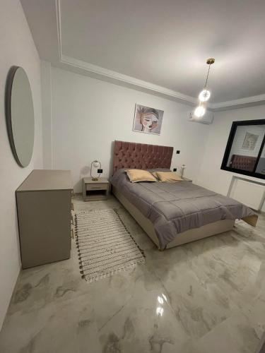 Schlafzimmer mit einem Bett, einem Tisch und einem Spiegel in der Unterkunft Un appartement S+1 agréable et spacieux ( terrasse) in Nabeul