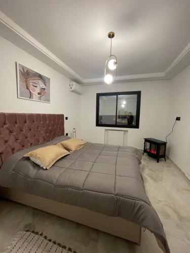 een slaapkamer met een groot bed en een flatscreen-tv bij Un appartement S+1 agréable et spacieux ( terrasse) in Nabeul