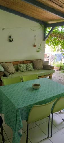 a green table and chairs in a room with a couch at Chambre d'hôtes pieds dans l'eau in Grande Anse