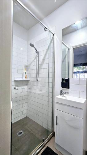 La salle de bains blanche est pourvue d'une douche et d'un lavabo. dans l'établissement Airport stay, à Melbourne