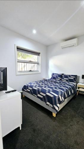 a bedroom with a bed and a tv and a window at Airport stay in Melbourne