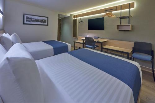 a hotel room with two beds and a dining room at City Express by Marriott Cancun Aeropuerto in Cancún