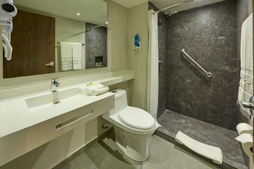 a bathroom with a toilet and a sink and a shower at City Express by Marriott Cancun Aeropuerto in Cancún