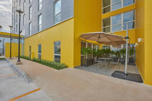 a yellow building with a table and an umbrella at City Express by Marriott Cancun Aeropuerto in Cancún