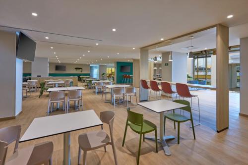 a cafeteria with tables and chairs in a building at City Express by Marriott Cancun Aeropuerto in Cancún